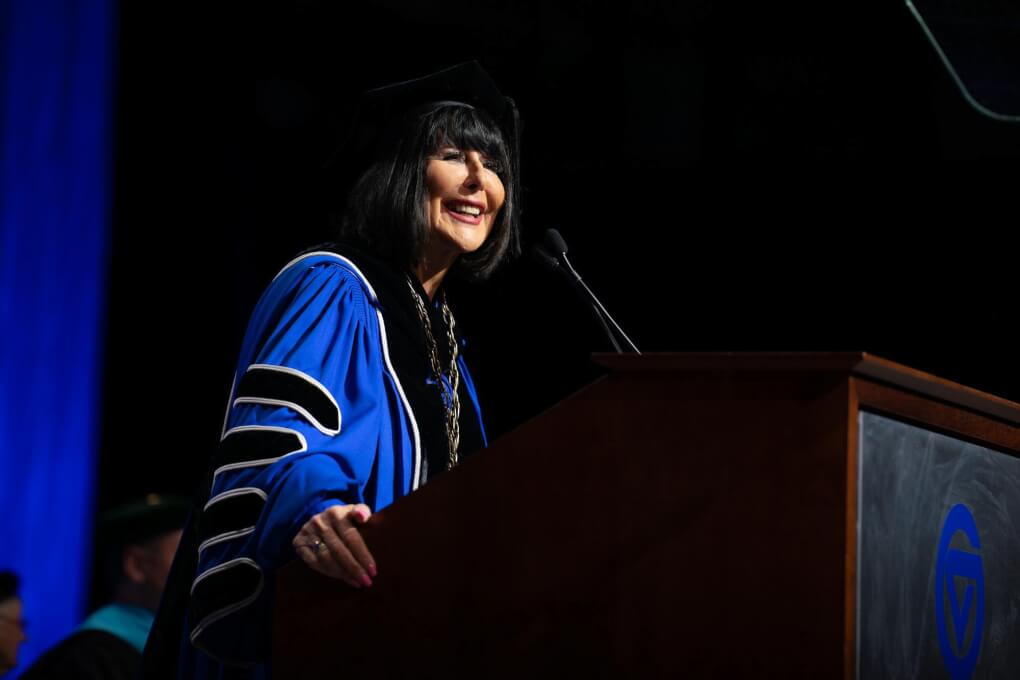 President Mantella smiles at a podium at commencement
